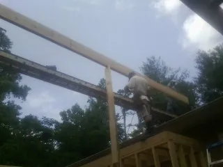 Carpenter setting a ridge beam over a new addition frame — Ice Dam Removal by Roofing Brothers in Avenue
