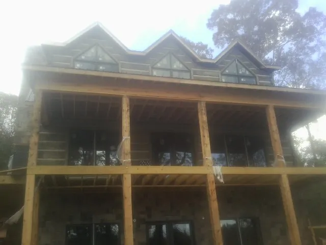 Dormers and porch framing on a large log home under construction — Roof Coating work by our crew in Avenue