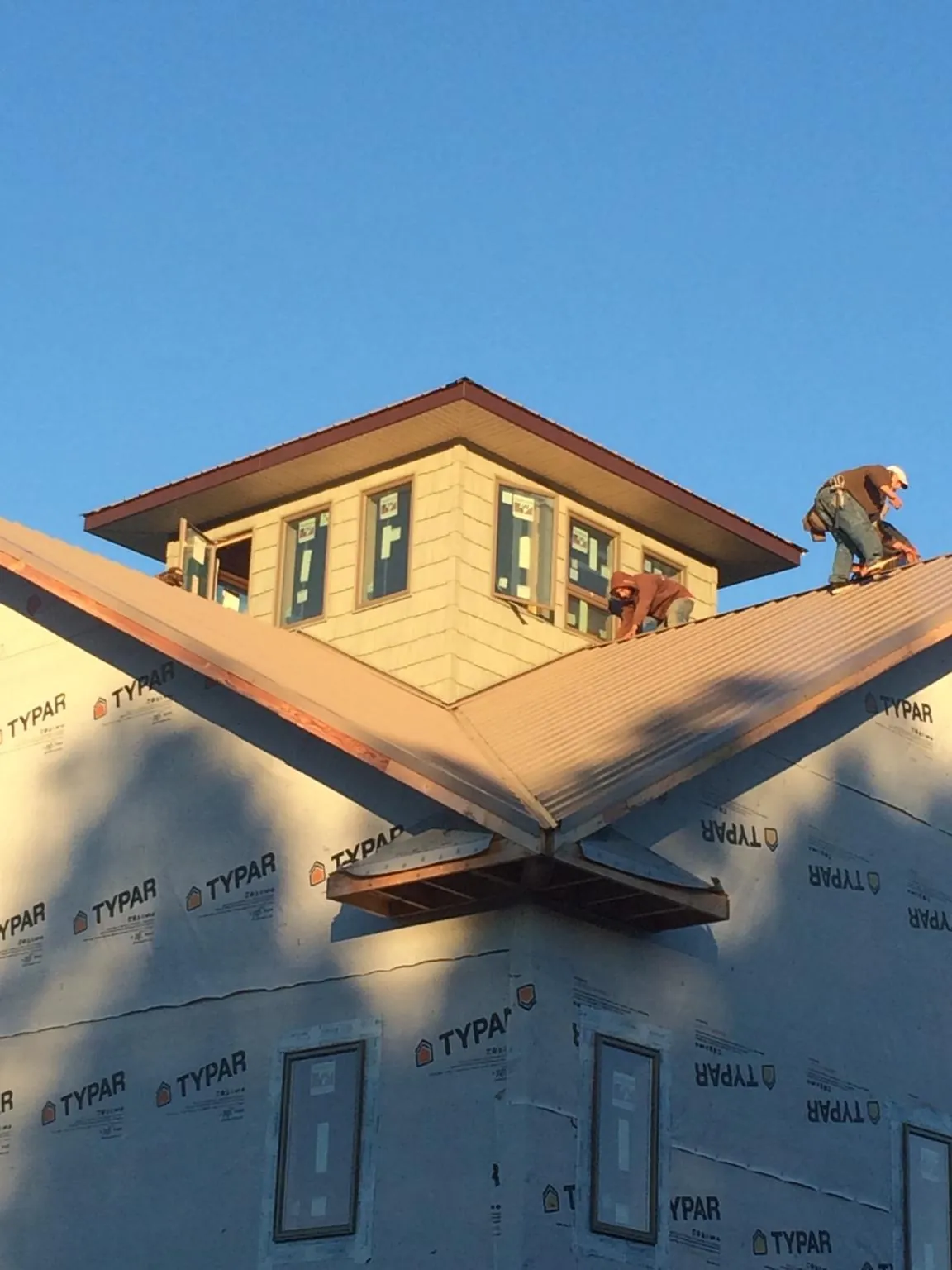 Roofers working around a rooftop cupola on a new metal roof at sunset — Roof Waterproofing in Avenue by Roofing Brothers